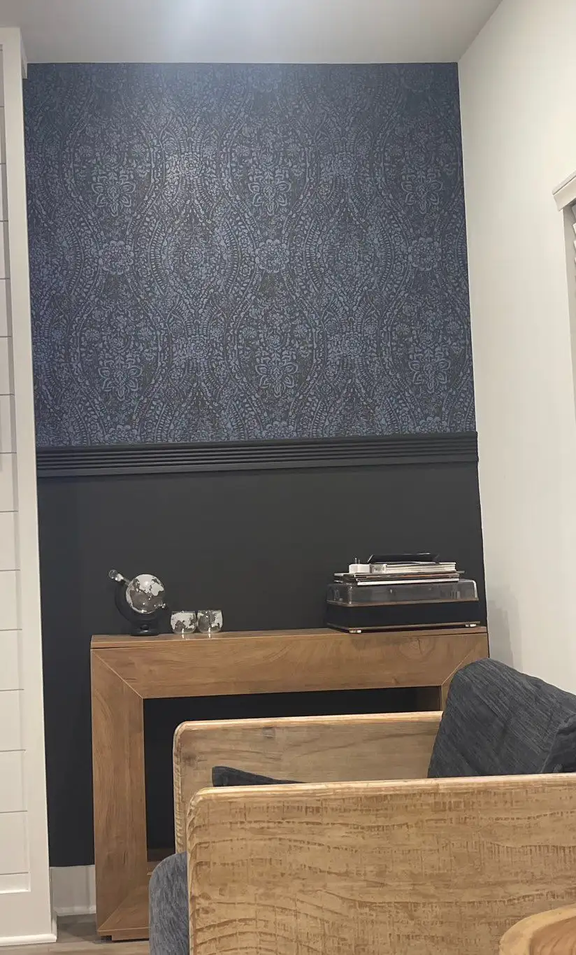 Living-room accent wall in dark charcoal textured wallpaper above a black painted lower section and a wood console